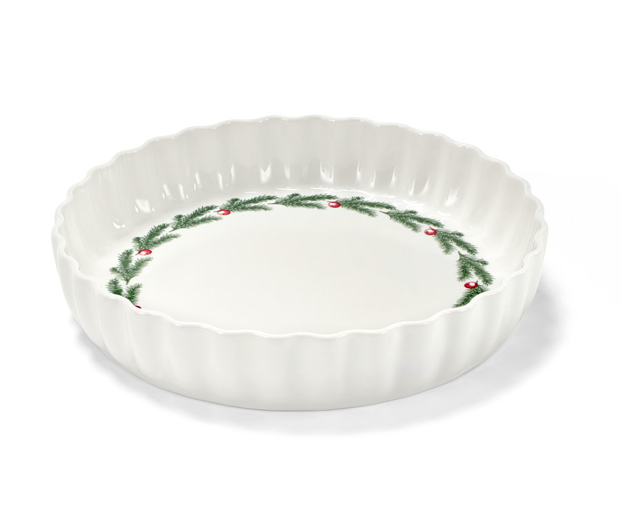 Un moule à tarte blanc avec un motif de Noël de branches de sapin et de baies rouges.