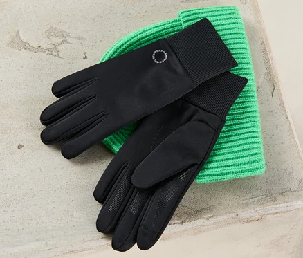 Des gants coupe-vent noirs reposent sur un bonnet en tricot vert.
