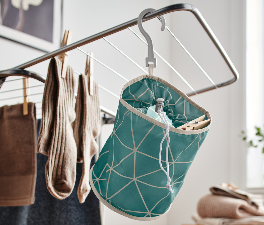 Un sac à pinces à motifs verts est suspendu à un séchoir à linge.