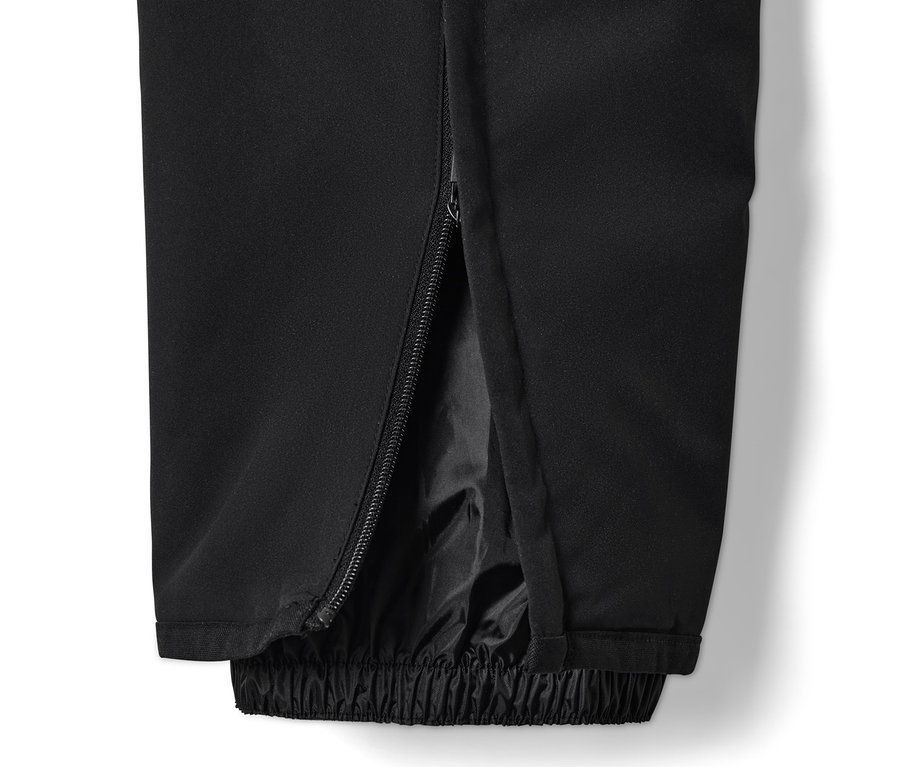 Détail d'un pantalon de ski high-tech noir avec fermeture éclair sur le côté de la jambe.
