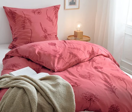 Une parure de lit en jersey d'hiver à motif floral et un livre ouvert sont posés sur le lit.