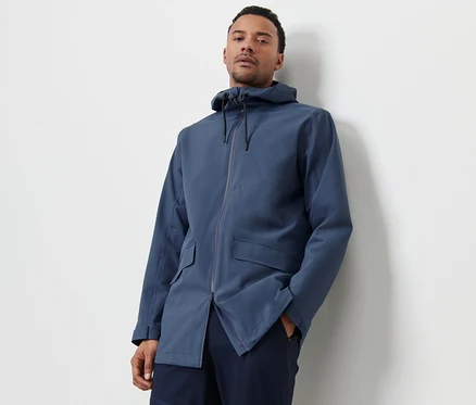 Un homme pose en veste d’extérieur bleue.