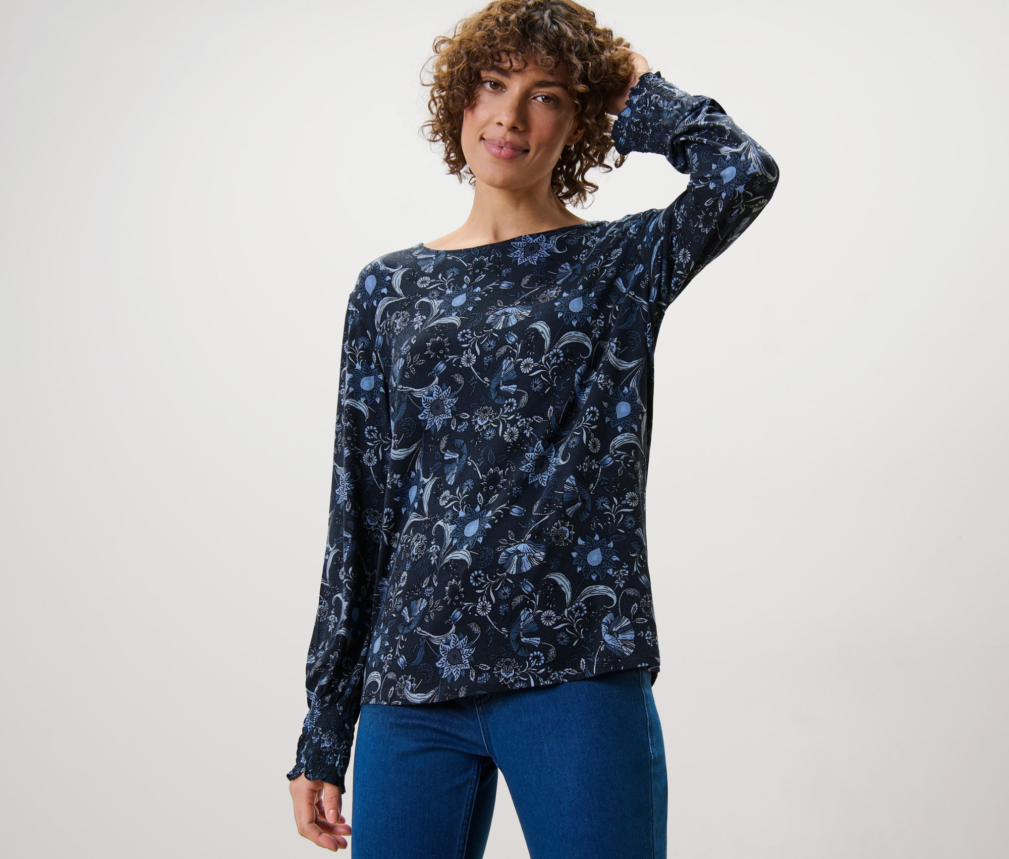 Femme posant en blouse imprimée et jean.