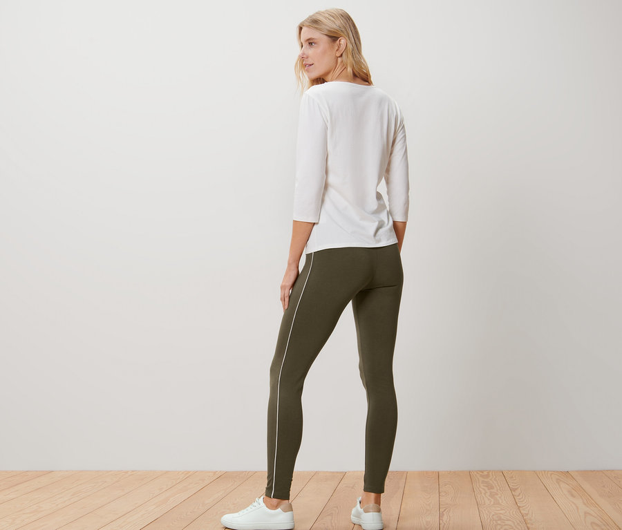 Femme vue de dos portant un chemisier blanc et un legging passepoilé vert olive.