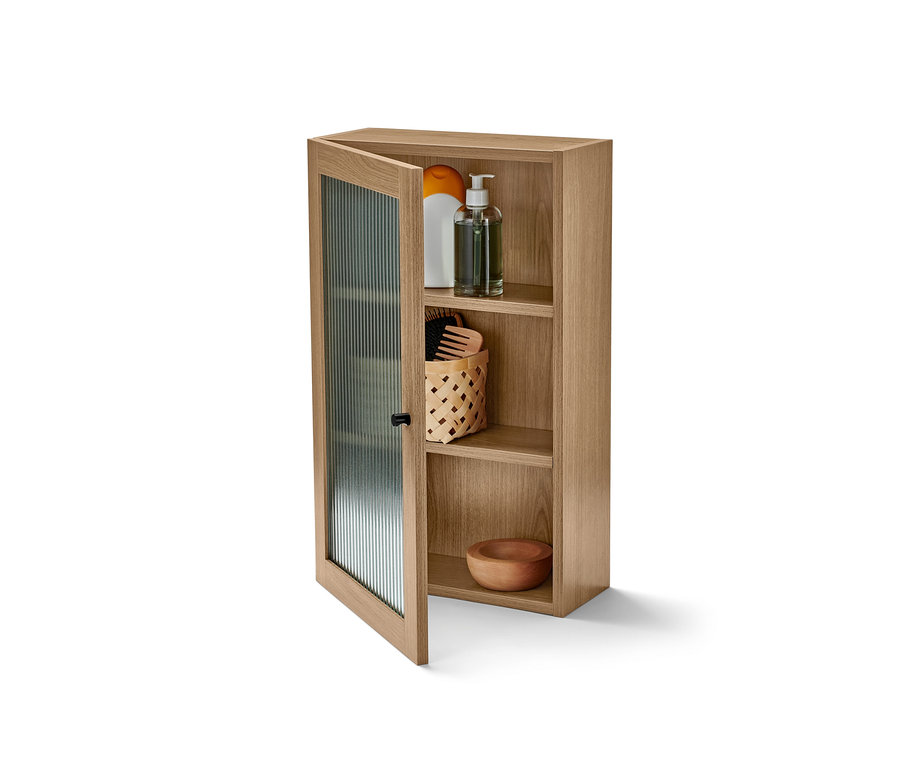 Armoire murale ouverte avec porte en verre strié et produits rangés.