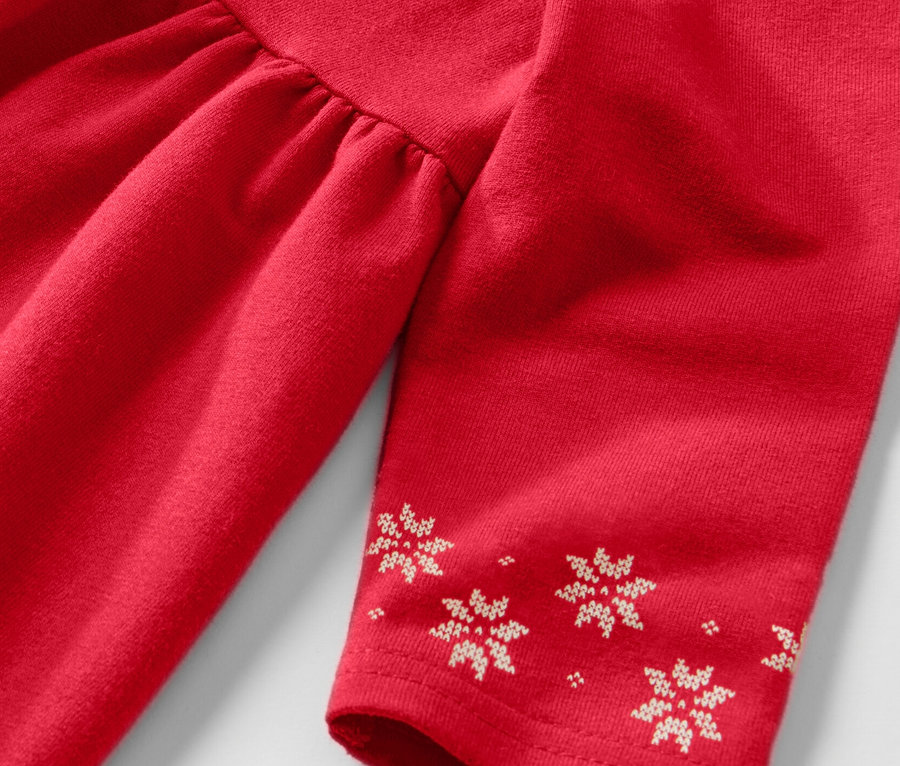 Détail d'une robe en sweat enfant rouge à manches longues avec un motif de flocons de neige.