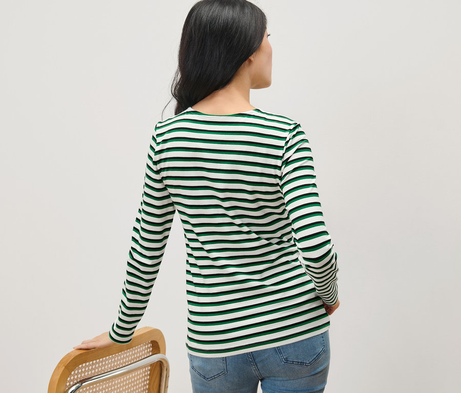 Une femme, vue de dos, porte un haut à manches longues rayé multicolore.