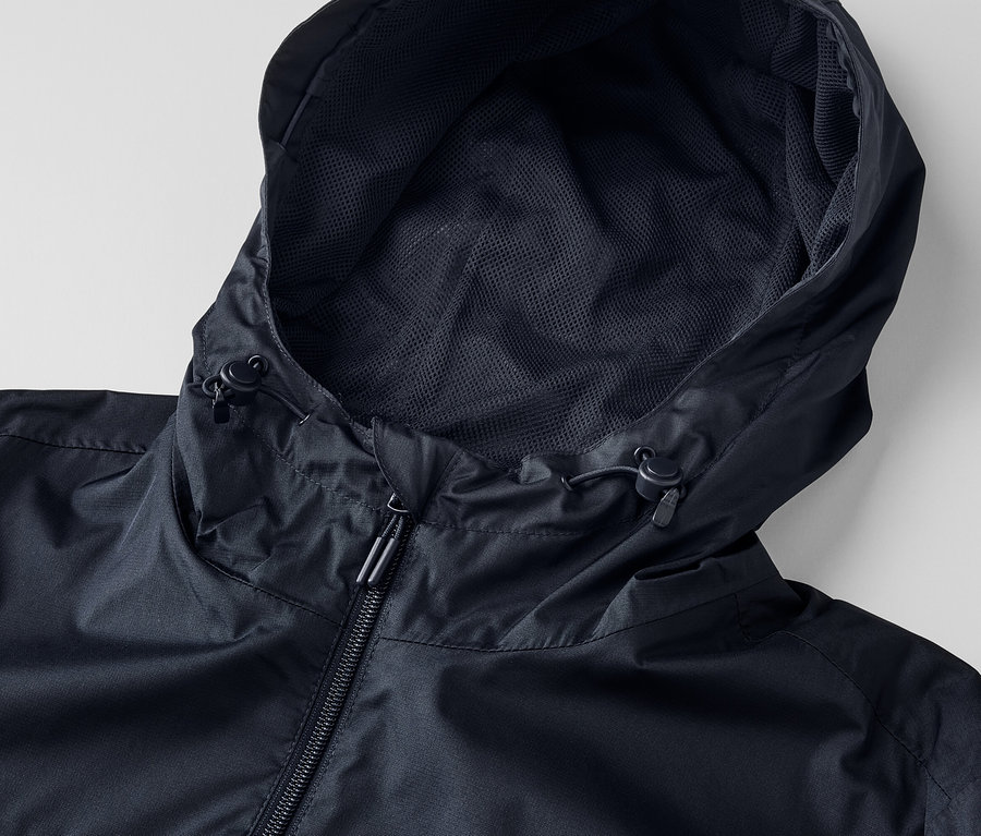 Gros plan sur une veste de pluie unisexe noire avec capuche et fermeture éclair.