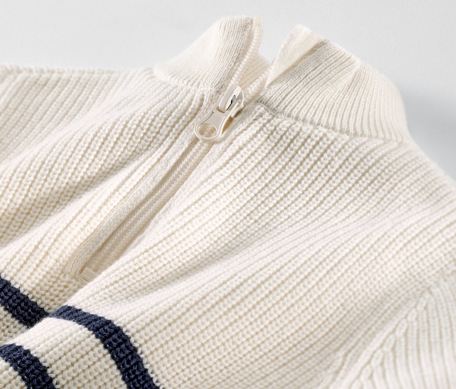 Gros plan sur un pull camionneur pour enfant avec une fermeture éclair blanche et des rayures bleu foncé.