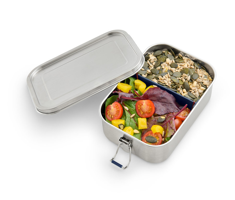 Boîte repas à emporter ouverte avec tomates, salade et graines de courge.