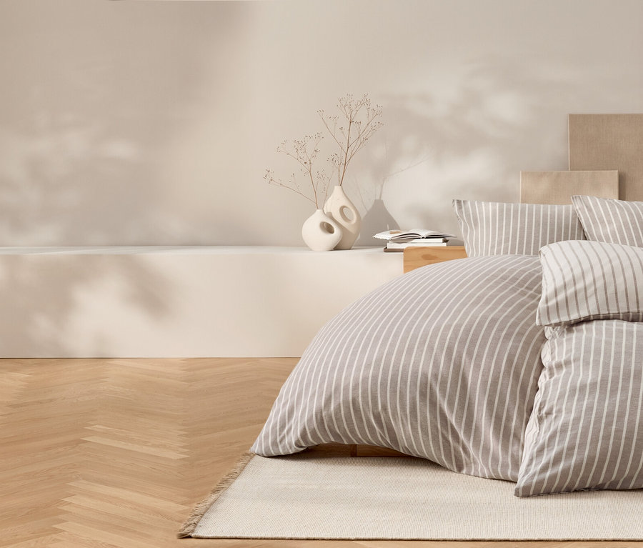 Chambre avec literie à rayures, parquet et vases décoratifs.