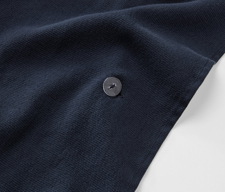 Gros plan sur un poncho de bain 2 en 1 bleu marine avec un bouton.