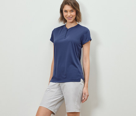 Femme posant dans un t-shirt de sport à demi fermeture éclair et un short.