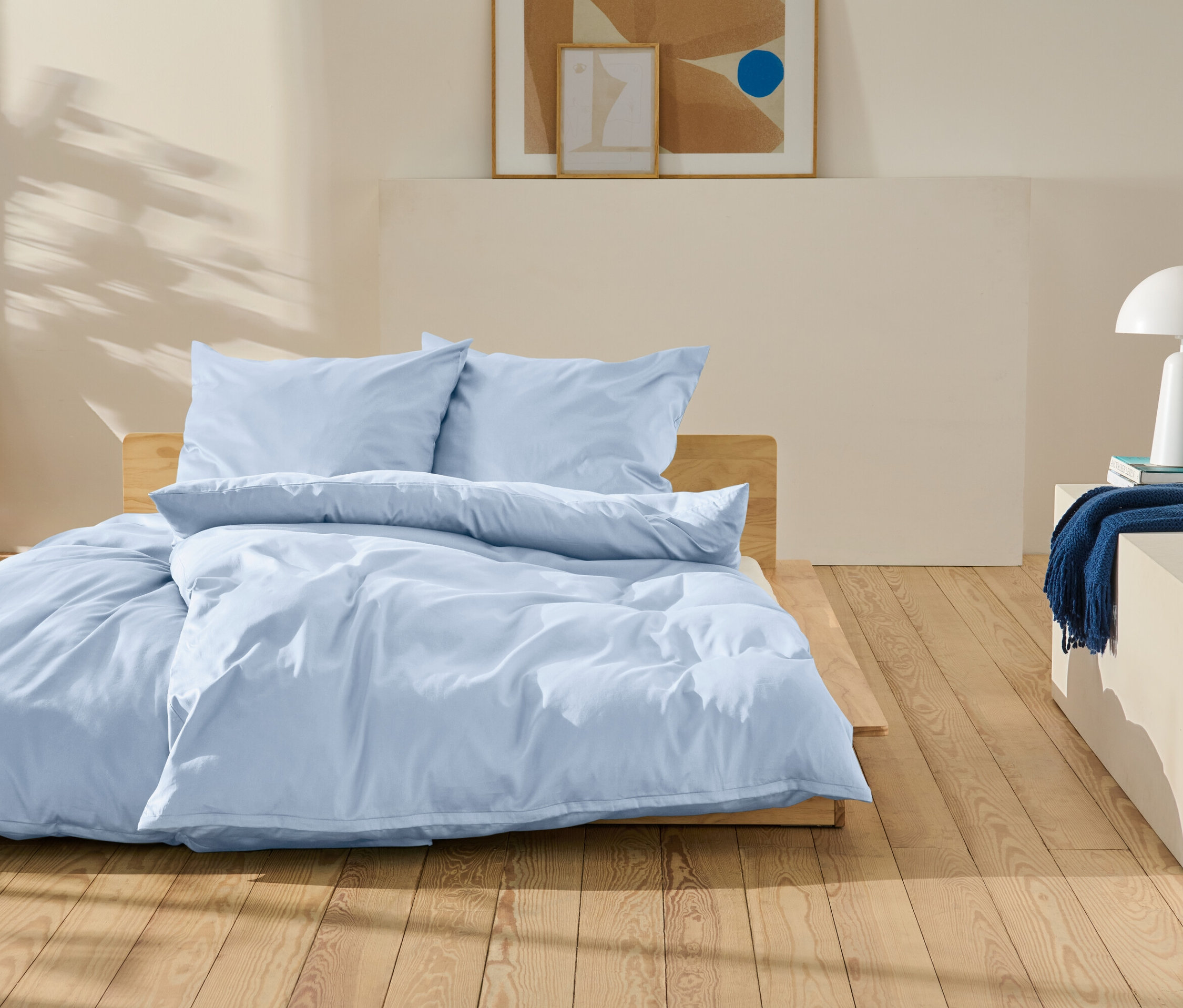 Linge de lit bleu clair sur un lit en bois dans une chambre.