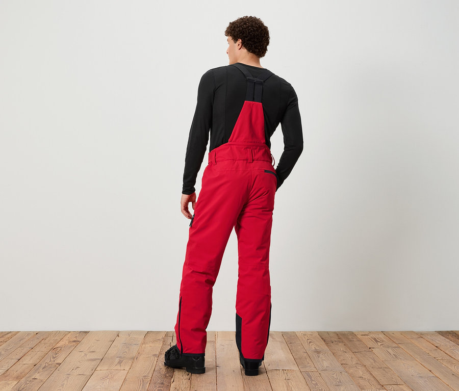 Homme vu de dos portant une salopette de ski rouge et un t-shirt noir.