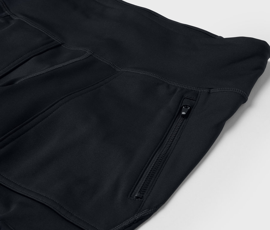 Détail d'un pantalon de sport noir avec poches et fermeture éclair.
