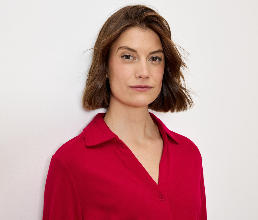 Portrait d'une femme aux cheveux bruns portant un chemisier rouge à col.