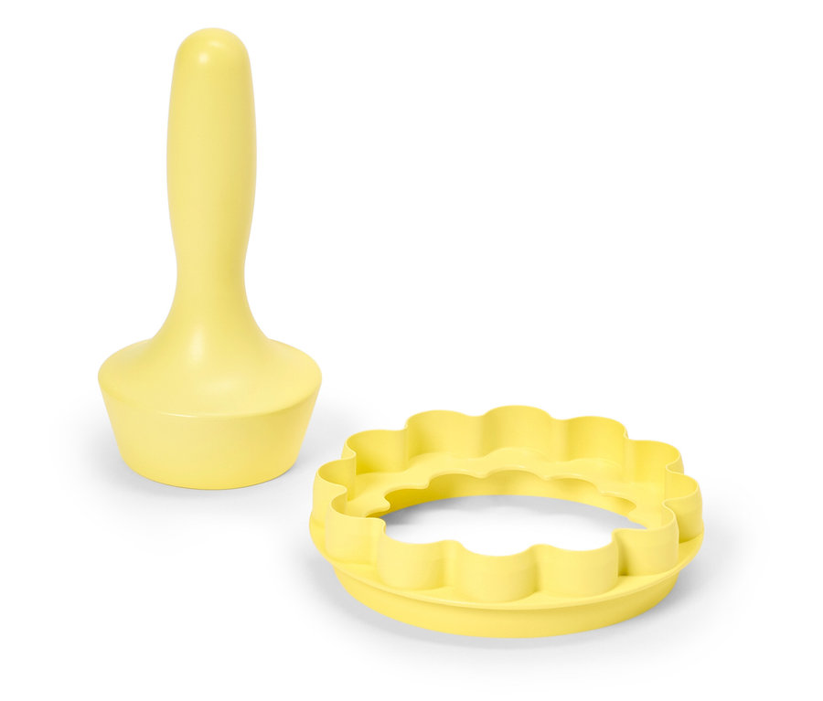 Emporte-pièce à pâte jaune avec manche et emporte-pièce rond à bord ondulé sur fond blanc.