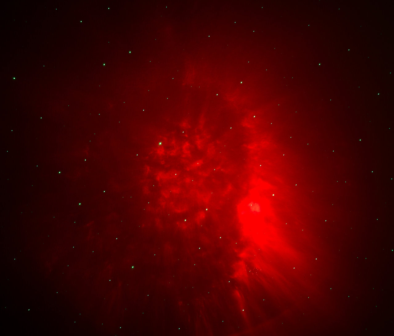 Une nébuleuse rouge avec des étoiles sur un fond sombre.