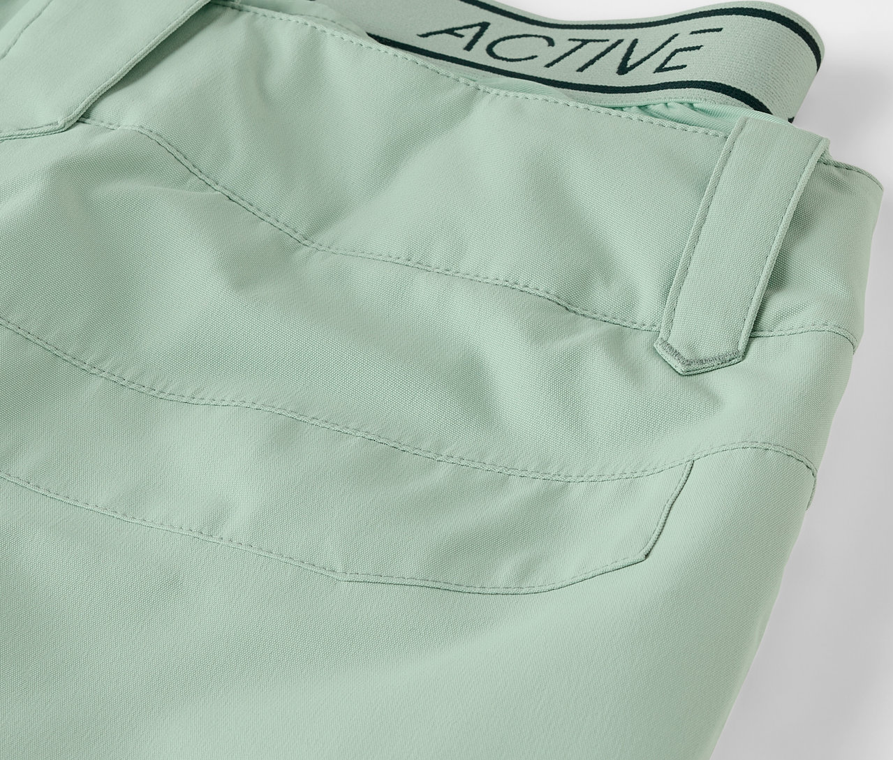 Détail d'un pantalon vert clair avec poche et ceinture portant l'inscription ACTIVE.
