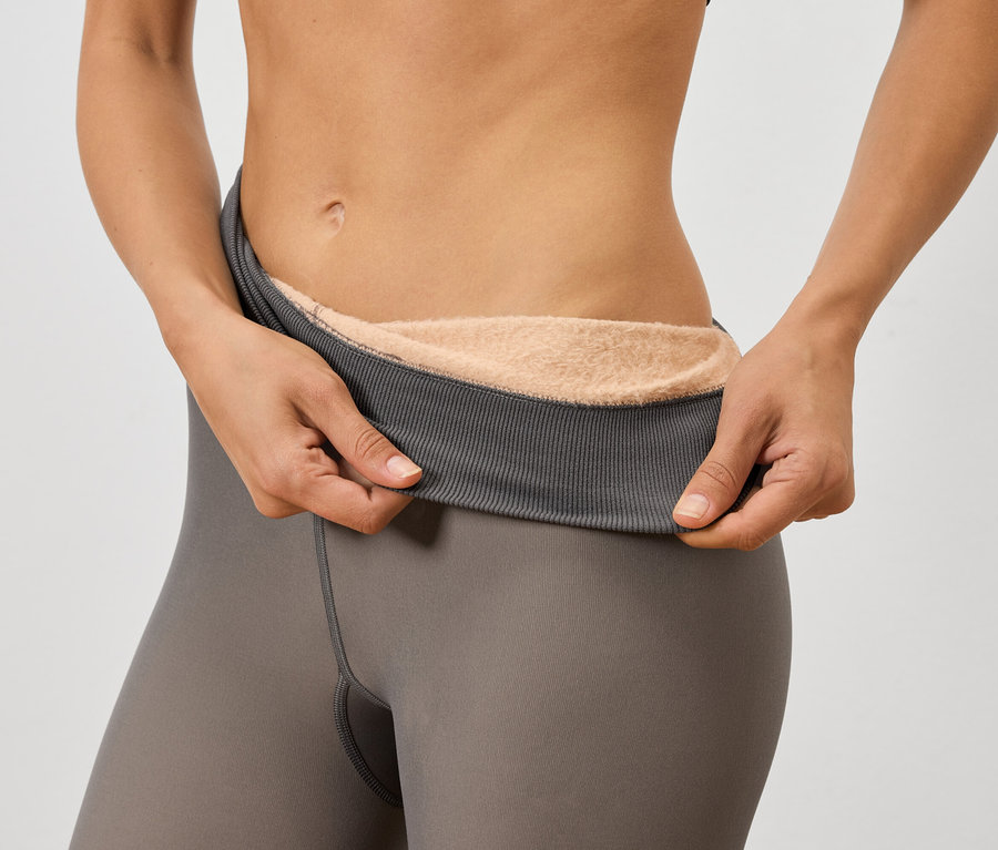 Femme tenant des leggings gris avec une doublure chaude.