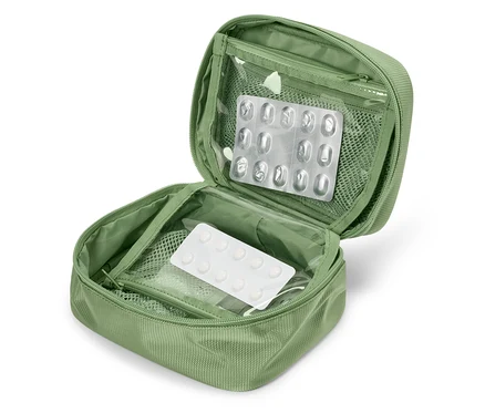 Trousse de premiers secours verte ouverte avec des plaquettes alvéolées de médicaments à l'intérieur.