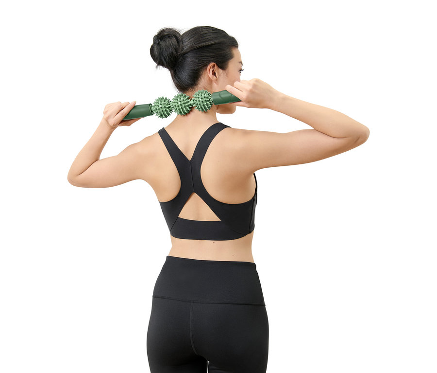 Femme utilisant un rouleau de massage vert pour le cou.