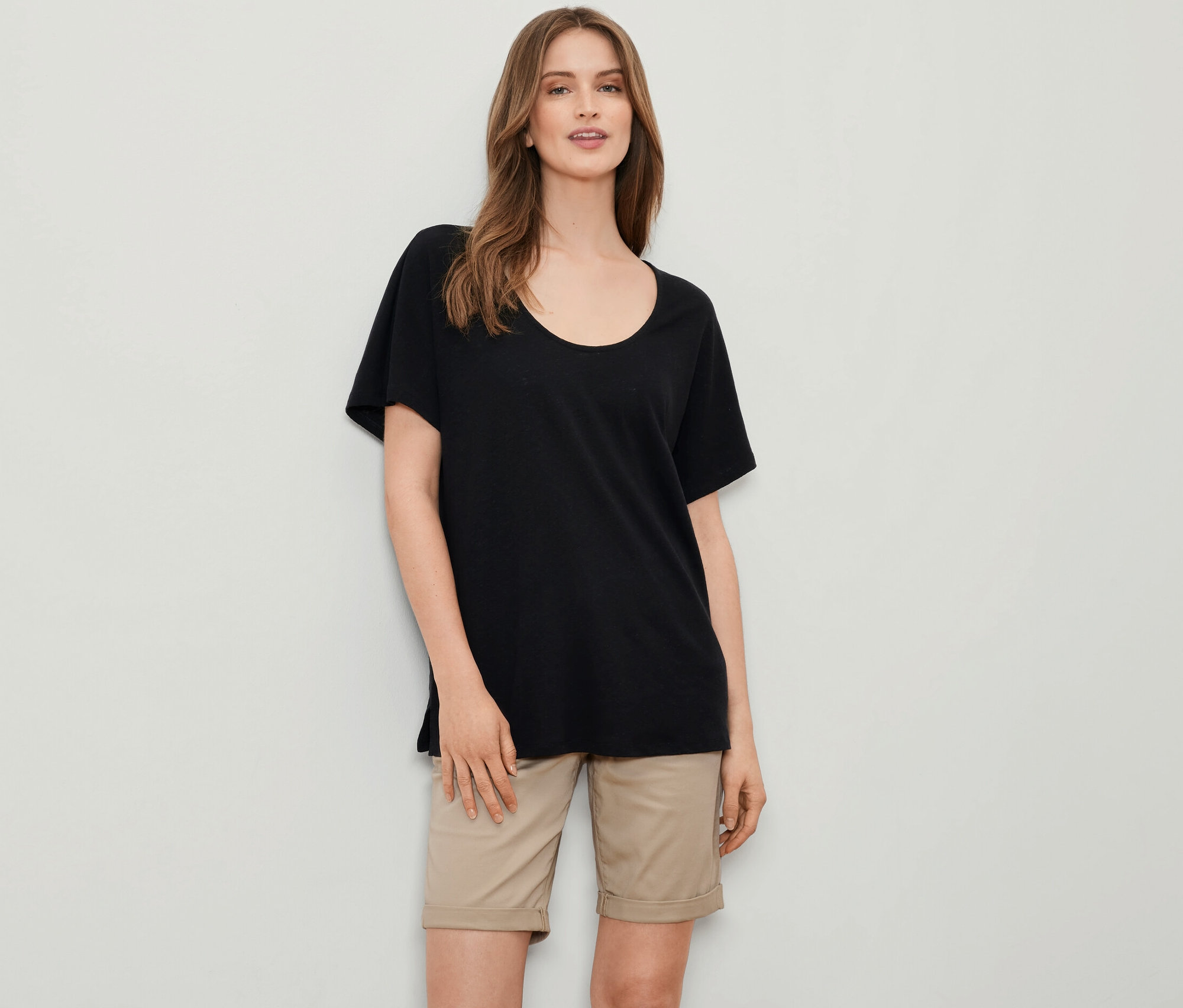 Une femme porte un t-shirt noir en lin mélangé et un short beige.