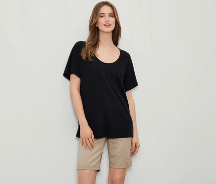 Une femme porte un t-shirt noir en lin mélangé et un short beige.