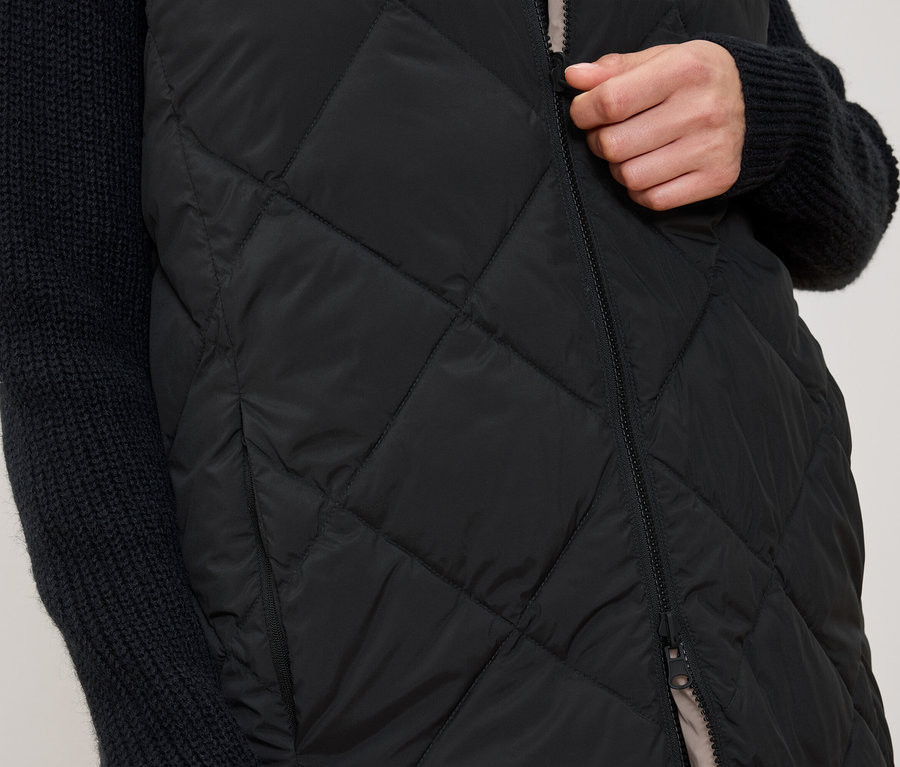 Femme fermant un gilet noir matelassé.