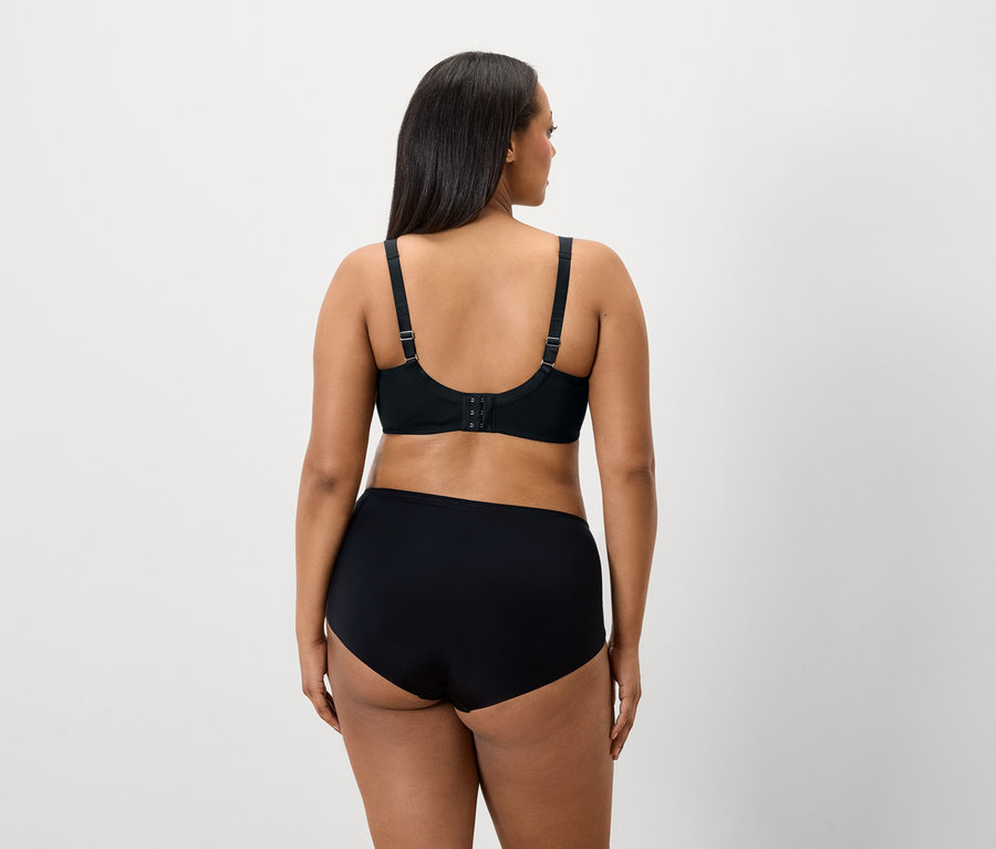 Vue arrière d'une femme aux cheveux foncés portant un soutien-gorge et une culotte noirs.