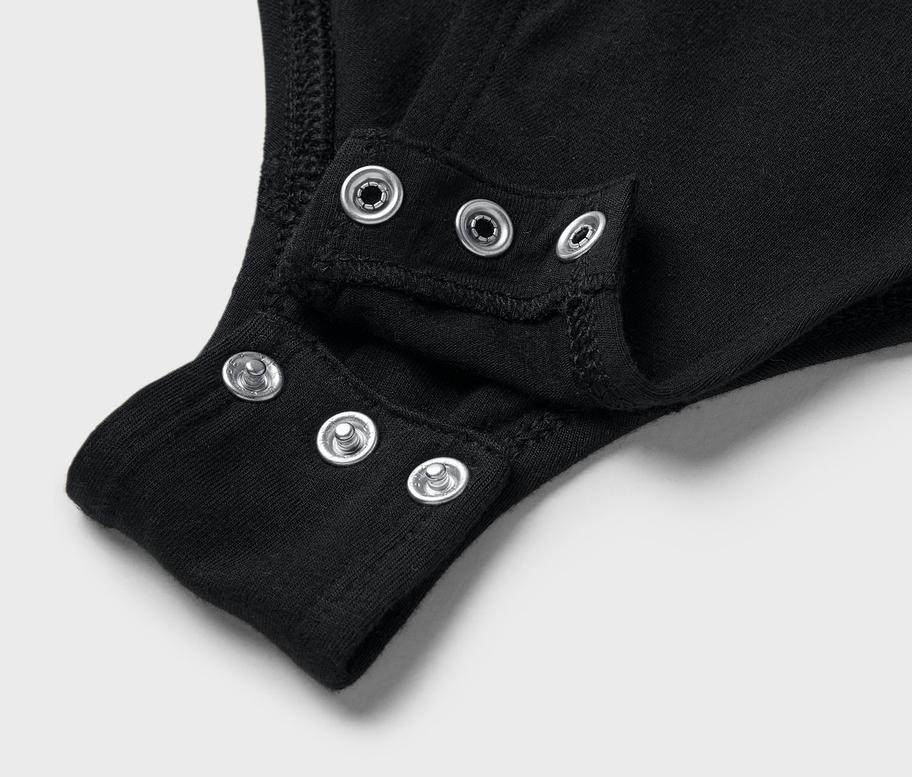 Gros plan sur un body noir avec des boutons-pression à l'entrejambe.