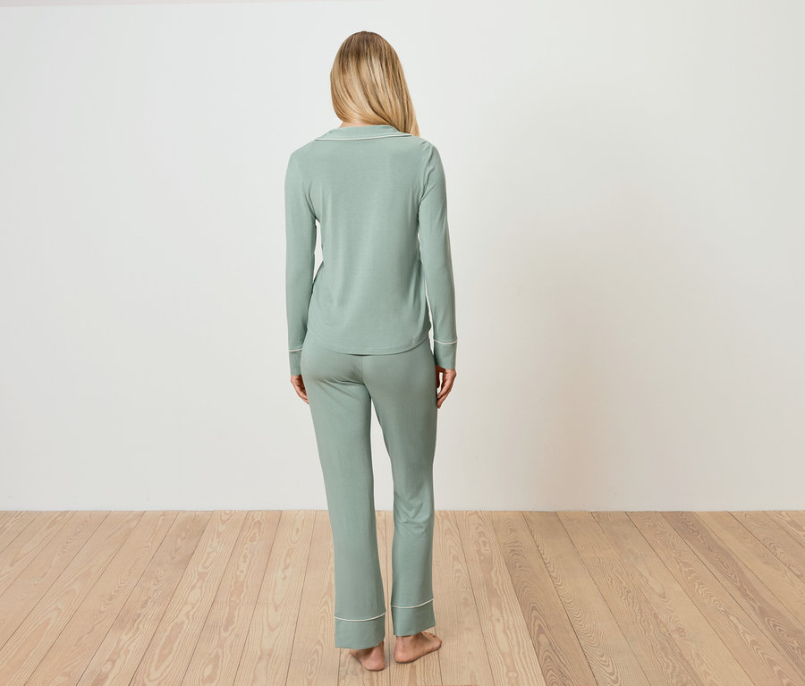 Une femme, vue de dos, porte un pyjama vert clair.