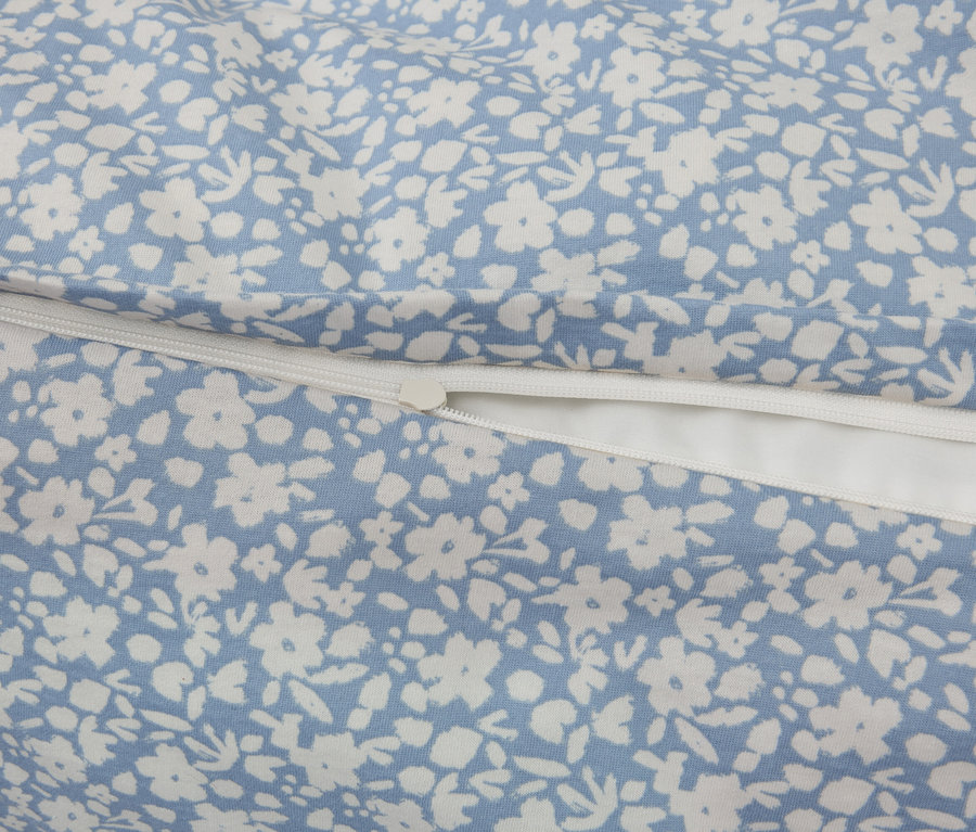 Gros plan d'un tissu à fond bleu avec un motif floral blanc, complété par une fermeture éclair blanche.