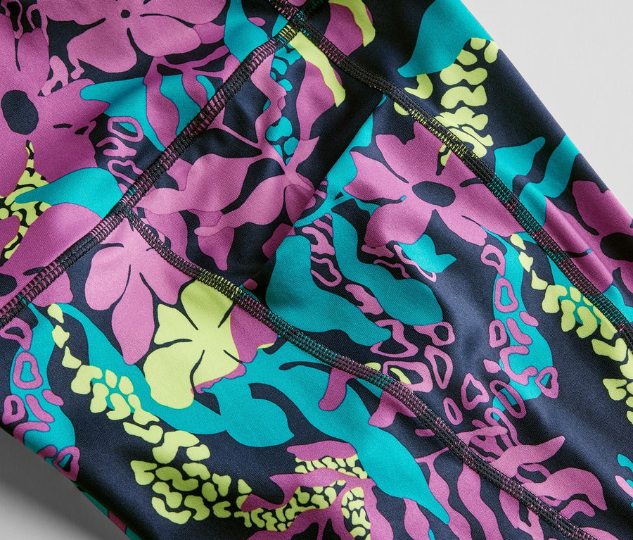 Gros plan sur un collant de sport 3/4 avec un imprimé intégral de fleurs et de feuilles roses, turquoise et jaunes.