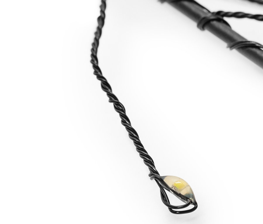 Gros plan sur un des 3 piquets solaires avec fil noir et lumière LED.