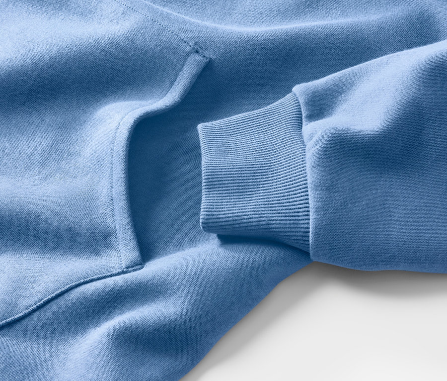 Gros plan sur un sweat à capuche bleu clair, montrant une poche et une manche côtelée.