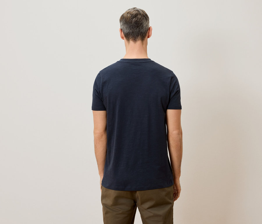 Homme vu de dos portant un t-shirt bleu marine et un pantalon kaki.