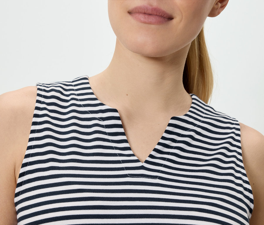 Une femme porte un haut sans manches rayé bleu et blanc avec un col en V.
