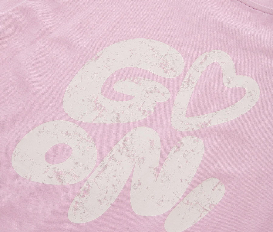 Vue détaillée d'un t-shirt rose avec l'inscription "Go On !"