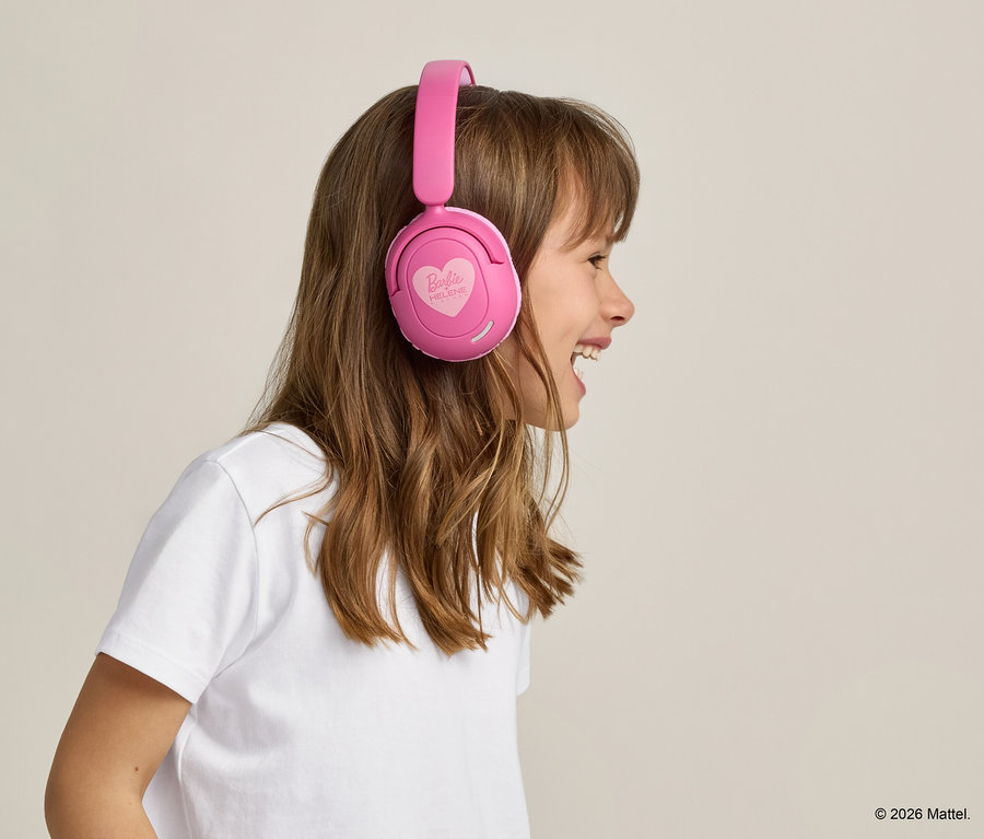 Vue de profil d'une jeune fille souriante aux longs cheveux bruns portant un t-shirt blanc et un casque rose Barbie.