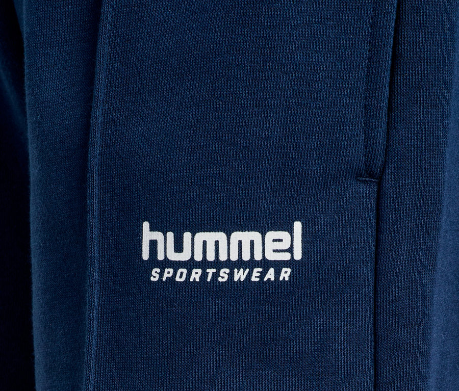 Gros plan d'un pantalon de survêtement Hummel bleu marine avec un logo blanc.
