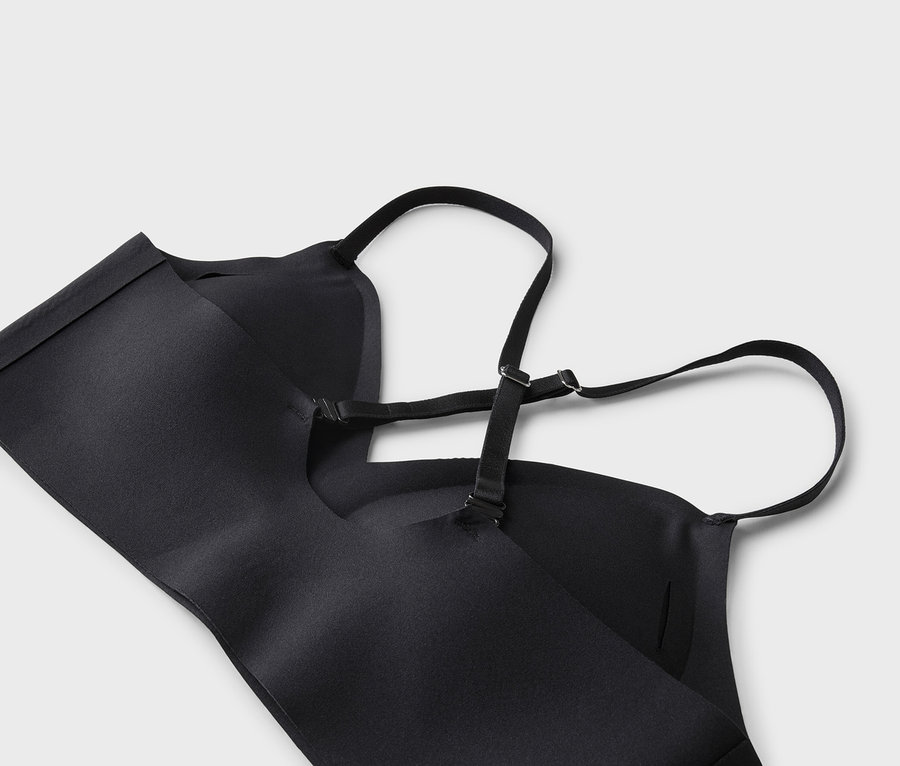 Gros plan d'un soutien-gorge noir avec bretelles réglables sur fond gris clair.