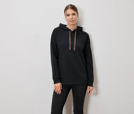 Femme portant un sweat à capuche noir et un pantalon.