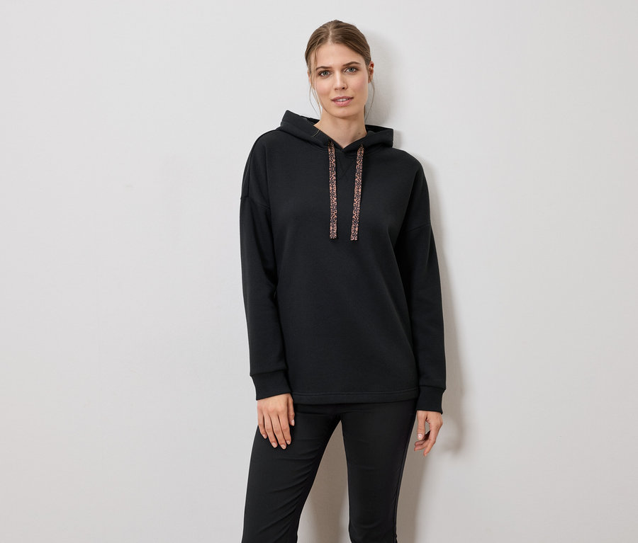 Femme portant un sweat à capuche noir et un pantalon.