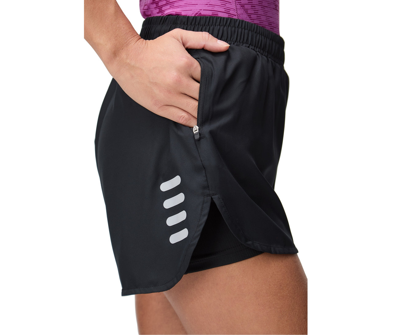 Femme mettant sa main dans la poche zippée d'un short noir avec des bandes réfléchissantes.