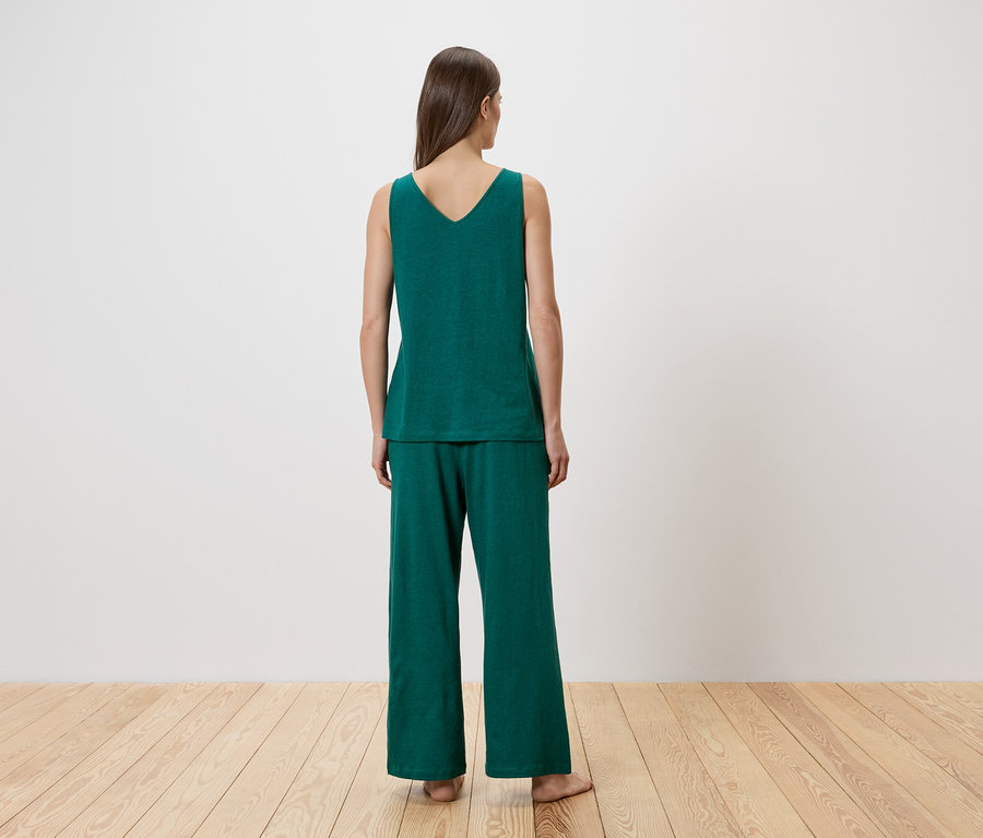 Femme vue de dos portant un débardeur et un pantalon vert émeraude.