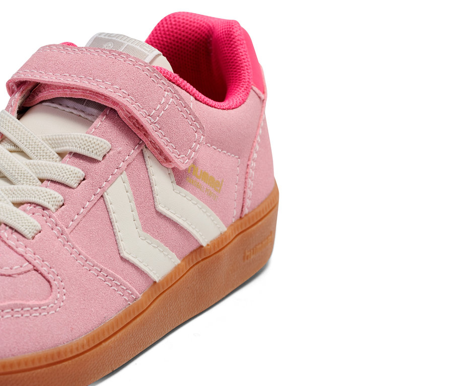 Gros plan d'une seule basket rose clair avec fermeture velcro et lacets.