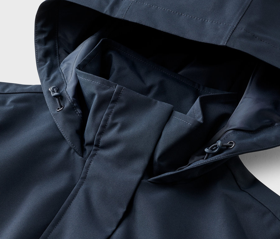 Gros plan d'une veste bleu marine avec capuche et cordon de serrage.