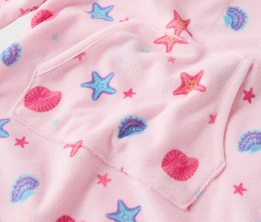 Gros plan sur un peignoir rose pour enfant avec un motif étoile de mer et coquillage et une poche plaquée.